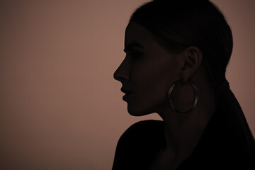 Silhouette of woman on brown background, profile portrait. Space for text