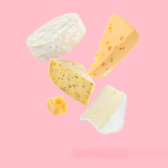 Different kinds of cheese falling on pink background