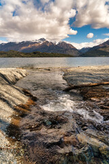 Hill side stream flooding down high cliffs into a Lake with the Southern alps mountain range  in the background