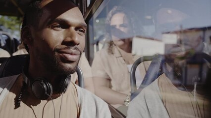 Young black man, with headphones, looking out the bus window. Cinematic 4k. - Powered by Adobe