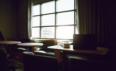 Coffree cup with computer laptop and bread on wooden table in cafe by bright window. in the morning people start working and have  breakfast