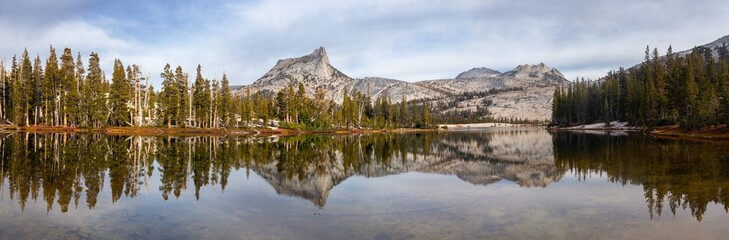 Fototapeta na wymiar Sierra Nevada Granite Mountain Peak Reflected in Calm Water of Treelined Lower Cathedral Lake. Scenic Yosemite National Park Panoramic Landscape, California USA