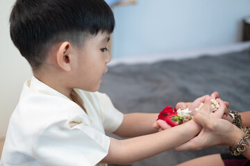 Little asian boy Giving a jasmine garland to mother On Thailand's National Mother's Day