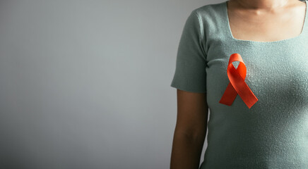 Studio shot of a person proudly wearing an HIV AIDS awareness red ribbon on their chest. Isolated...