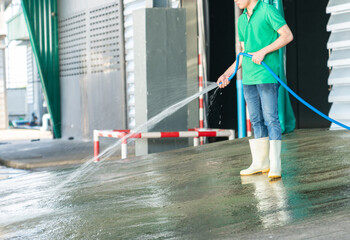 Staff cleaning floor with hoses washing the concrete floor with water jets.