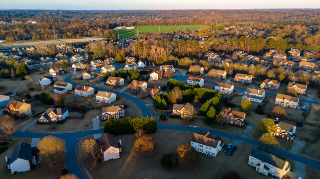 Aerial panoramic view of an upscale subdivision with housing cluster in suburbs of USA shot during golden hour