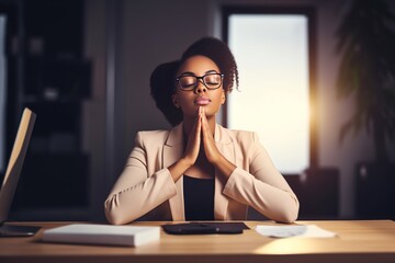 African ethnicity business woman doing yoga in the office with closed eyes - obrazy, fototapety, plakaty