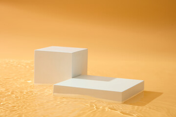 Rectangle and cube podiums in white color displayed against orange background. Mock-up for...