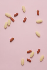 The tablets are randomly displayed on a pastel pink background. Empty space for text design. Tablets are a popular form and a low-cost way to make medicine but ensure safety and effectiveness
