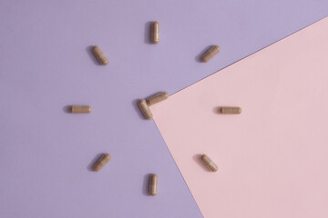 The hard gray capsules are arranged in a clock shape on a purple background. Functional foods are prepared in capsule form for easy storage and easy absorption by the body.