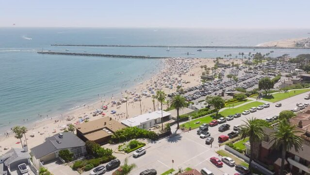 Drone shot of people relaxing on beach of Corona Del Mar, Newport Beach, California, West coast, USA. Overhead shot of residential houses with view of Newport Bay. Summer ocean landscape, 4k footage