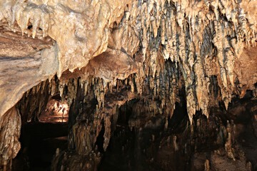 Stalactites and stalagmites raise ghostly fingers in the dim light of the limestone caves of  Tham...