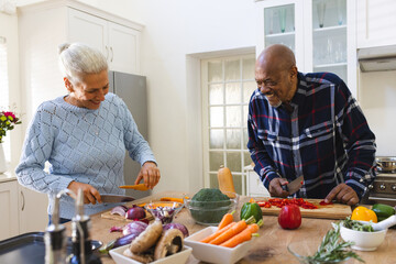 Happy diverse senior couple slicing butternut squash, preparing vegetables in kitchen © WavebreakMediaMicro
