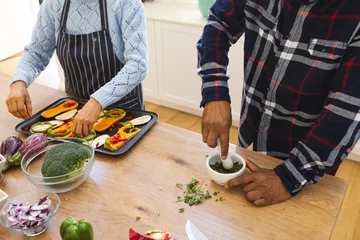  Midsection of diverse senior couple preparing healthy meal with vegetables in kitchen © wavebreak3