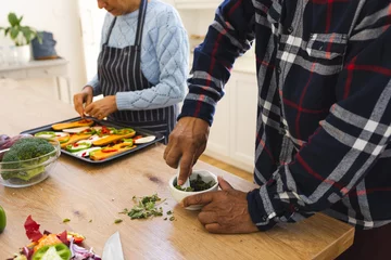  Midsection of diverse senior couple preparing healthy meal with vegetables in kitchen © wavebreak3
