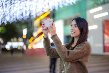 Woman use mobile phone to take photo in city at night