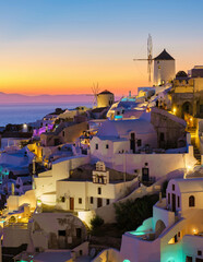 White churches an blue domes by the ocean of Oia Santorini Greece during sunset, a traditional...