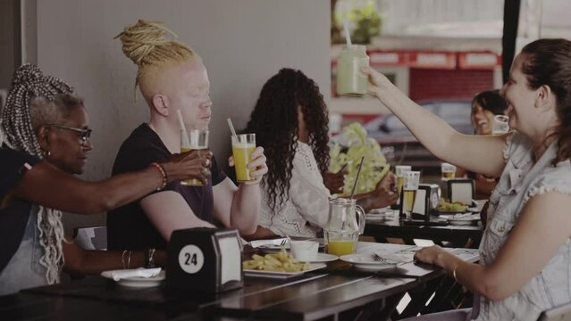 Group of different ages toasting at a table in an outdoor bar. Cinematic 4k.