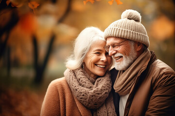 Fototapeta premium An elderly couple, a man and a woman, hugging in an autumn park. They look at each other with a loving gaze. Old people on a walk. Relationships in old age. Love and romance.