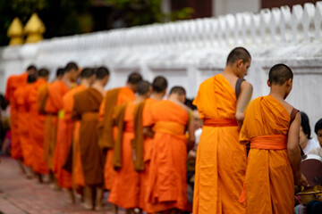 Buddhist alms giving ceremony in the early morning.Monks walk to collect alms and offerings.Sticky rice morning alms giving is held every day in Luang Prabang.Traditional ritual of alms giving in Laos - obrazy, fototapety, plakaty