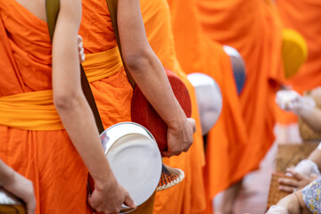 Buddhist alms giving ceremony in the early morning.Monks walk to collect alms and offerings.Sticky rice morning alms giving is held every day in Luang Prabang.Traditional ritual of alms giving in Laos - obrazy, fototapety, plakaty