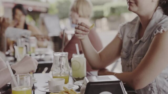 Young woman eating french fries in an outdoor bar. Cinematic 4k.