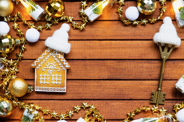 Tiny gingerbread house on wooden background with Christmas decor layout and copy space. Gift for New Year, Christmas. Building, project, moving to new house, mortgage, rent and purchase real estate