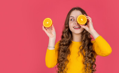 smiling teen girl hold orange fruit on pink background