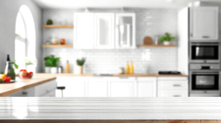 Fototapeta na wymiar Blurred view of modern kitchen with white furniture with wooden table