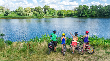 Family on bikes cycling outdoors, active parents and kids on bicycles, aerial view of family with...