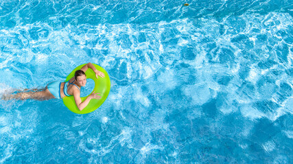 Active young girl in swimming pool aerial top view from above, teenager relaxes and swims on inflatable ring donut and has fun in water on family vacation, tropical holiday resort
 - obrazy, fototapety, plakaty