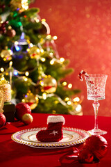 A woolen Christmas sock is placed on a round dish, displayed with baubles and a wine glass...