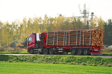 Forestry in Action. Truck Carrying a Heavy Load of Wooden Logs on the Roadside. Timber Transport. Side View of a Loaded Truck on the Highway. Lumber processing concept.