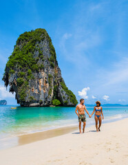 Fototapeta premium Railay Beach Krabi Thailand, the tropical beach of Railay Krabi, a couple of men in swimshort and women in bikini walking on the beach, 