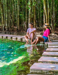 a couple of men and women visit the Emerald Pool and Blue Pond in Krabi Thailand, the tropical lagoon in a national park with trees, and mangroves with crystal clear water