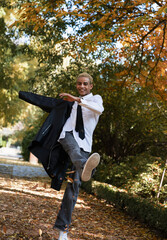 Young boy having fun jumping through the leaves in the park