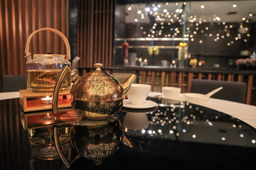 Teaset with golden tea pot and candle light against a bokeh background