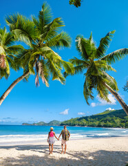 Anse Royale beach Mahe Seychelles, a couple of men and women on vacation in Seychelles walking at...