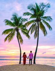 couple on the beach with palm trees watching the sunset at the tropical beach of Saint Lucia or St Lucia Caribbean. men and women on vacation in St Lucia a tropical island in the Caribbean