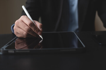 Closeup of businessman using stylus pen signing e-document on digital tablet. Business man planning...