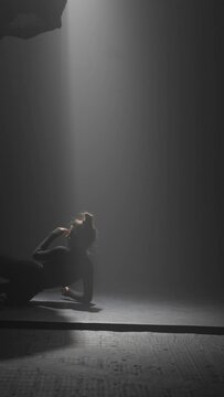 Incredible contemporary dance movements presented by the stylish young choreographer in a dark studio.