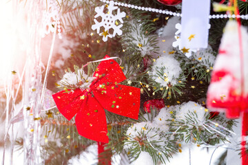 Festive background Christmas decoration with red Christmas bow, snowflakes in snow and snow covered fir branches