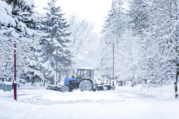 Snow machine tractor cleans snow on street in the city in winter in heavy snow.