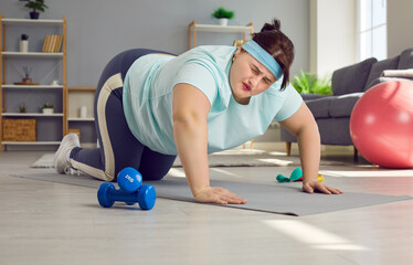 Young overweight woman having fitness workout at home. Chubby girl doing difficult exercise. Funny...