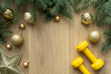 Dumbbells, Christmas gold bauble ornaments decorations and fir tree branches. Healthy fitness lifestyle winter holiday season composition with copy space. Gym workout, sport training flat lay concept.