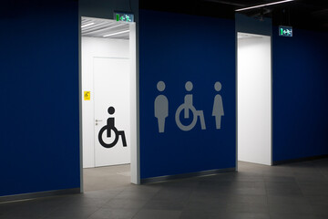 Entrance to the toilet with signs of a man, a woman and a wheelchair. Door to the restroom for...