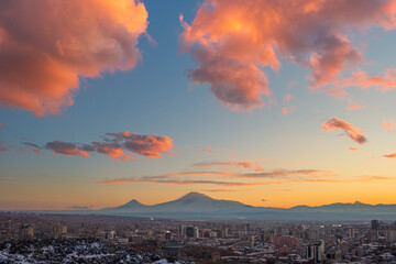 Wide angle panoramic view of the Yerevan city at sunset with the blue sky, orange clouds, and Ararat mounts