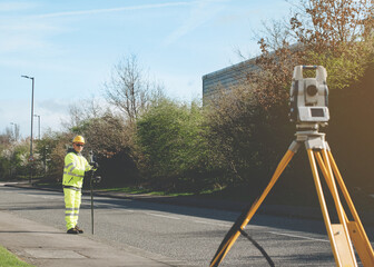 Surveyor doing road survey using modern robotic total station EDM before beginning of construction...