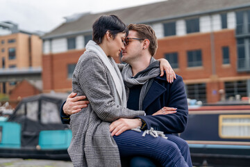 Handsome man and beautiful woman hugging and kissing each other as they walk around the city, having a fun time, lifestyle photo