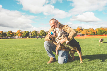An old man playing with his dog in the park